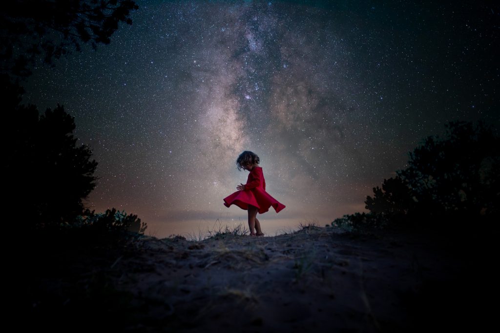 Photo of girl dancing in a red dress in front of the Milky Way